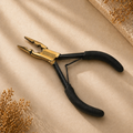 Pair of pliers with black handles and gold accents on a beige surface.