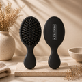 Two black hairbrushes on a beige surface with decorative elements.