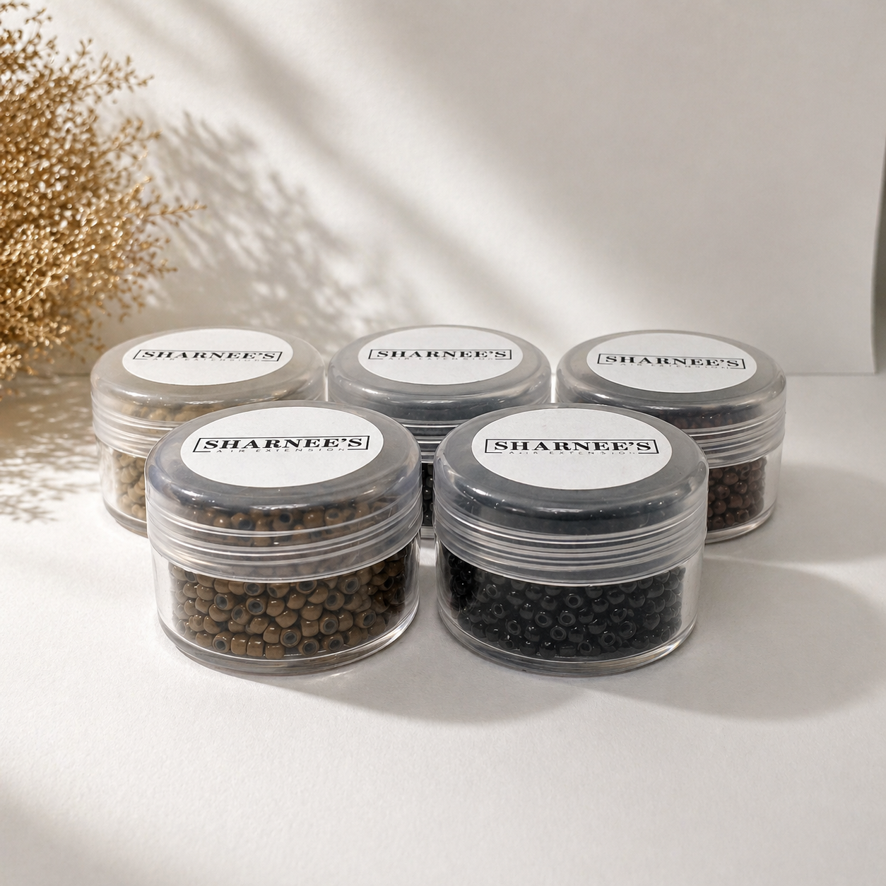 Set of small clear containers with black beads and 'Sharneen's' labels on a light background.