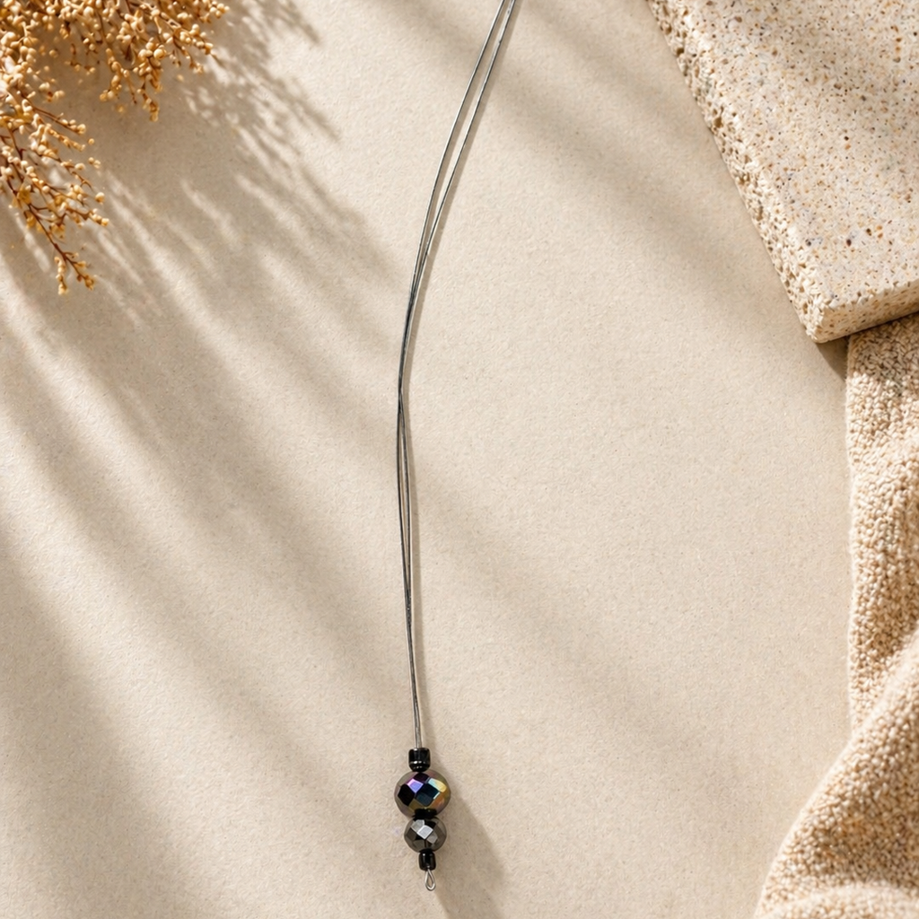 Thin metal rod with decorative beads on a textured beige surface