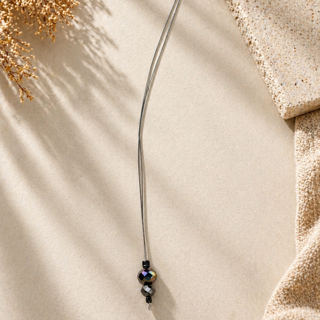 Thin metal rod with decorative beads on a textured beige surface